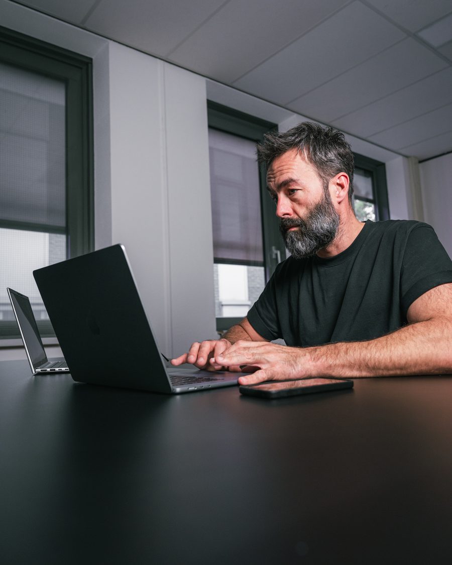 Ivo Klink typt op een laptop en kijkt op naar de camera