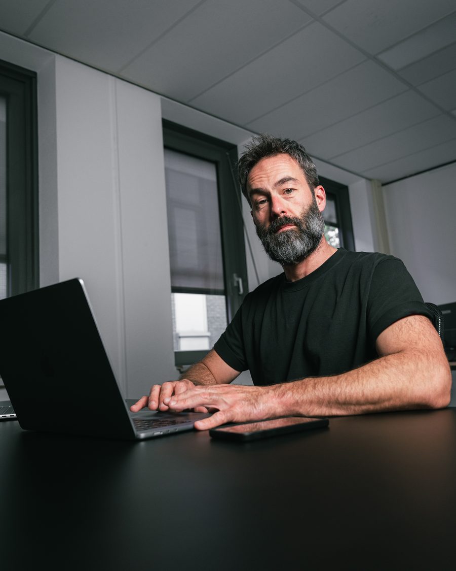 Ivo Klink achter zijn laptop kijkt met het hoofd iets schuin in de camera