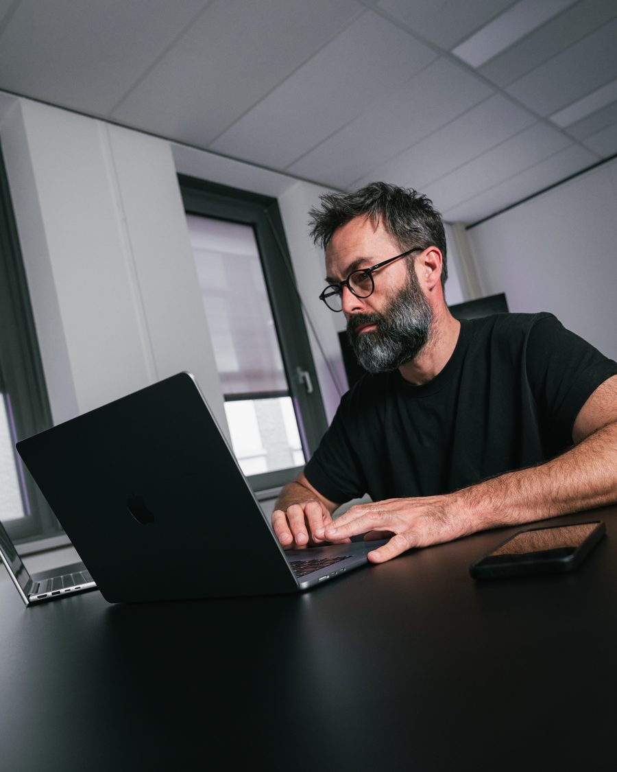 Ivo Klink met bril leest iets op het scherm van zijn laptop