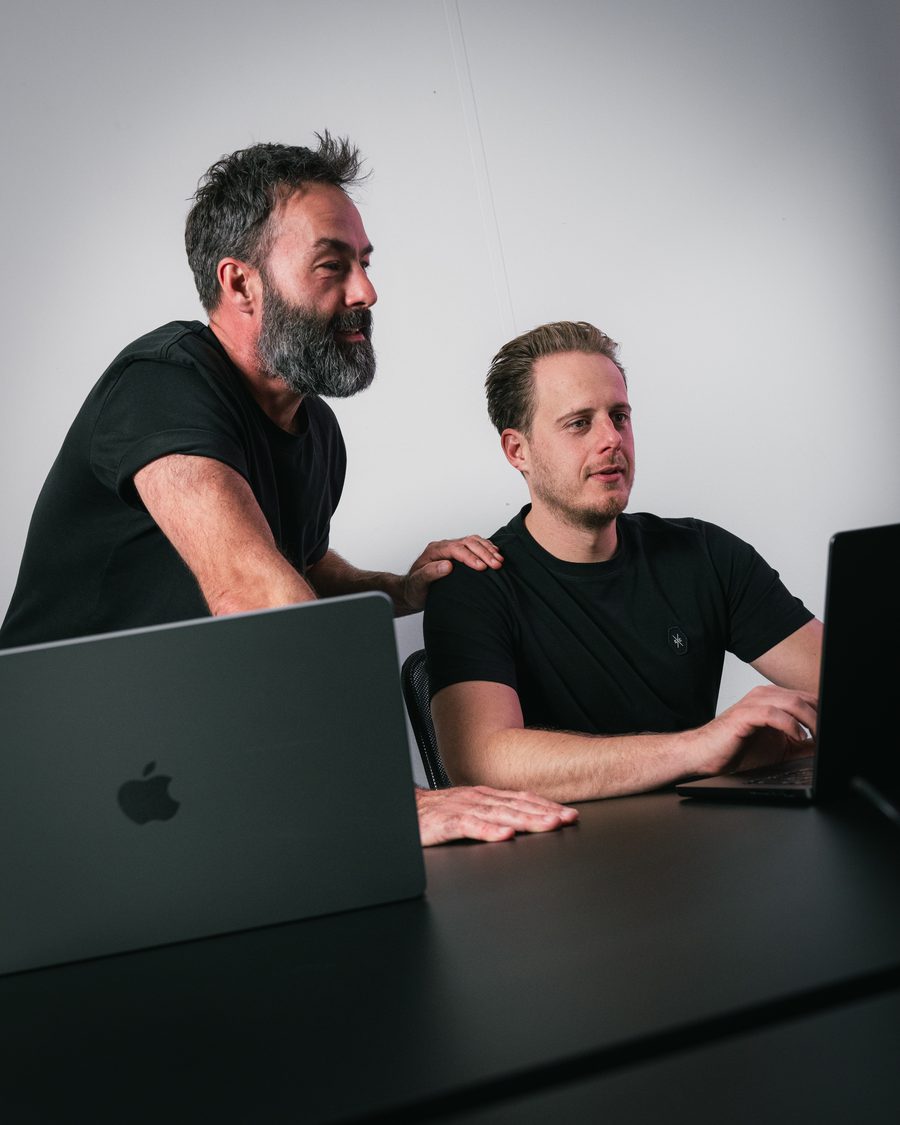 Ivo Klink staat met een hand op de schouder van Maurits den Dunnen, die aan een laptop zit, en samen kijken ze naar het scherm